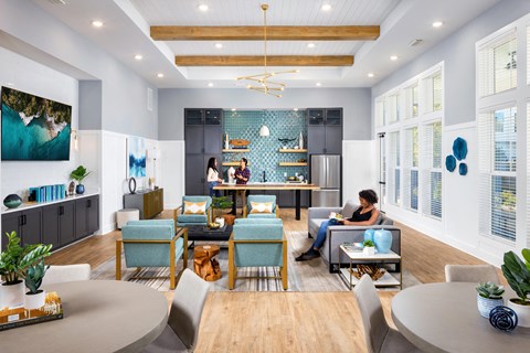 a living room with people sitting at a table and a kitchen